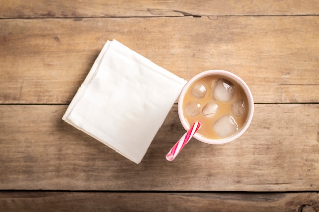 Erfrischender und verspannender Eiskaffee in einem Glas auf einem hölzernen Hintergrund. Konzept Coffeeshop, Durst stillen, Sommer. Flache Lage, Draufsicht