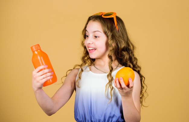 Erfrischender Vitaminsaft Gesundheitswesen Vitamin-Sommerdiät Natürliche Vitaminquelle Glückliches Mädchen trinkt frischen Orangensaft Sommerurlaub kleines Mädchen in modischen Gläsern Verliebt in gesunde Ernährung