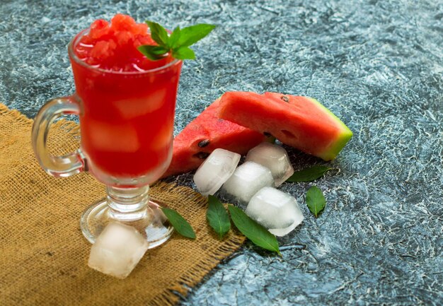 Erfrischender Wassermelonen-Smoothie in einem Glas und einem Blatt Minze auf schwarzem Hintergrund Kopierbereich