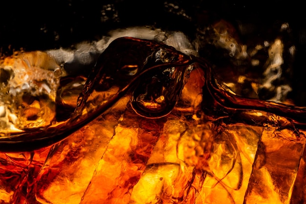 Erfrischungsgetränkglas mit Eisspritzer auf dunklem Hintergrund Cola-Glas im Feierpartykonzept