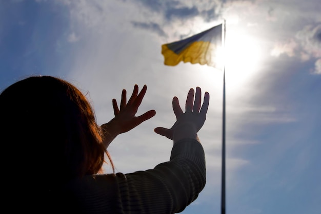 Erhobene Hände zum Himmel vor dem Hintergrund der Flagge der Ukraine Gebet um Hilfe und Segen für das Land Ukraine Schutz für die Nation