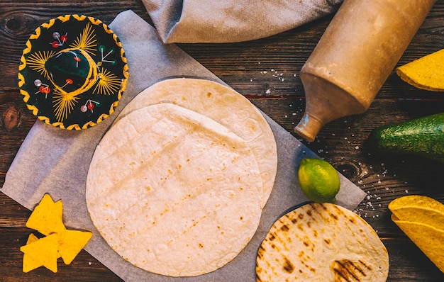 Erhöhte Ansicht der mexikanischen Tortilla des köstlichen Weizens und der geschmackvollen Nachos auf Holztisch mit Nudelholz