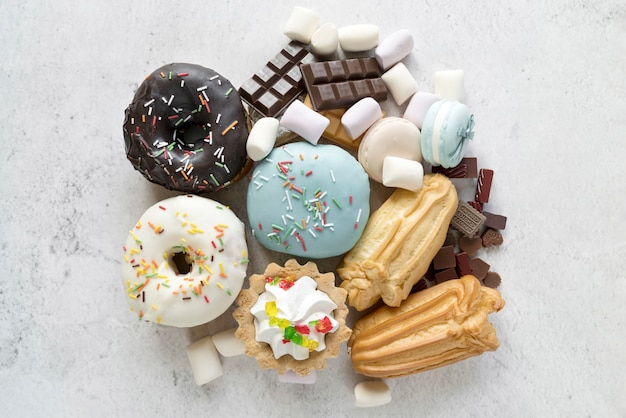 Foto erhöhte ansicht des verschiedenen süßigkeitenlebensmittels auf weißzement maserte hintergrund
