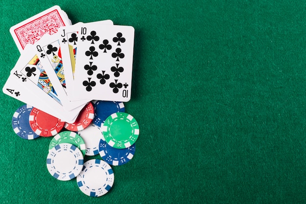 Foto erhöhte ansicht von royal flush clubs und chips auf grünem pokertisch