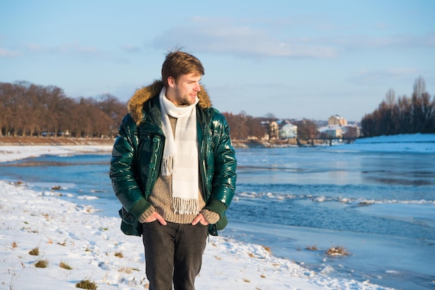 Erholungskonzept. Aktive Freizeit. Mann, der im Winter reist. Warme Kleidung für die kalte Jahreszeit. Wintermode. Winterferien. Aktive Erholung. Gehender verschneiter Naturhintergrund. Mann genießt den Januar im Freien.