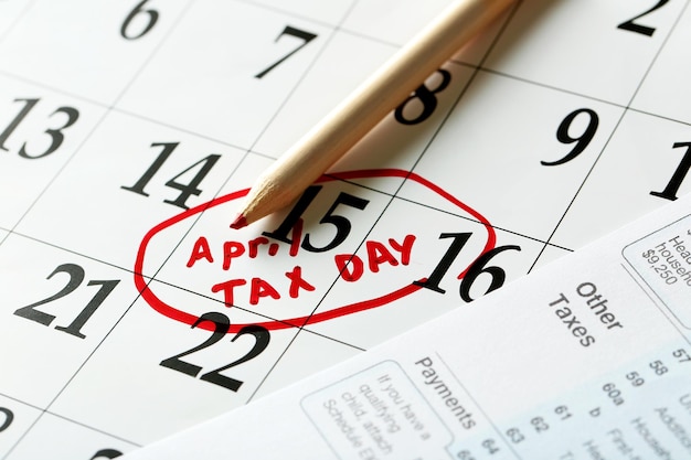 Erinnerung an den Steuertag im April in einem Kalender mit Steuerformular und Bleistift aus nächster Nähe