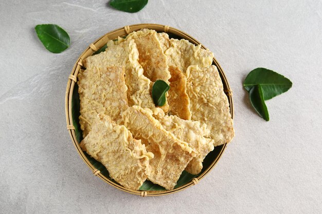 eripik tempe o chips de tempeh en un plato de madera Rebanadas de tempeh cubiertas con harina y fritas crujientes