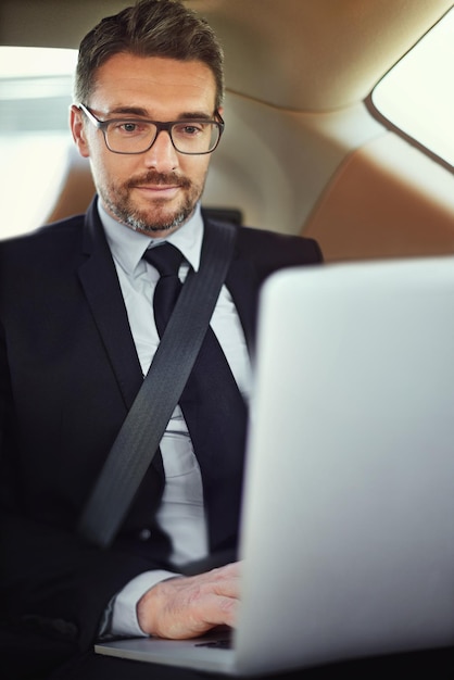 Erledigen der Arbeit auf dem Weg ins Büro Schnappschuss eines Geschäftsmanns auf dem Rücksitz eines Autos