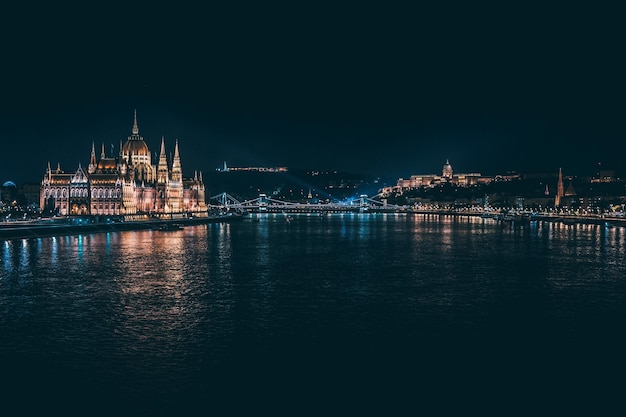 Erleuchtetes ungarisches Parlamentsgebäude am Fluss vor klarem Himmel bei Nacht