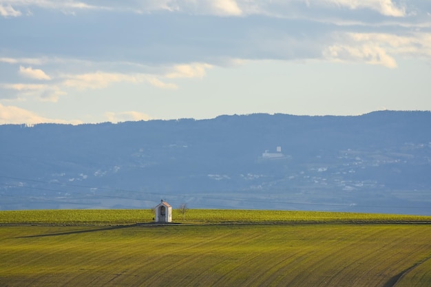 Ermita entre campos verdes y un paisaje con casas y bosque