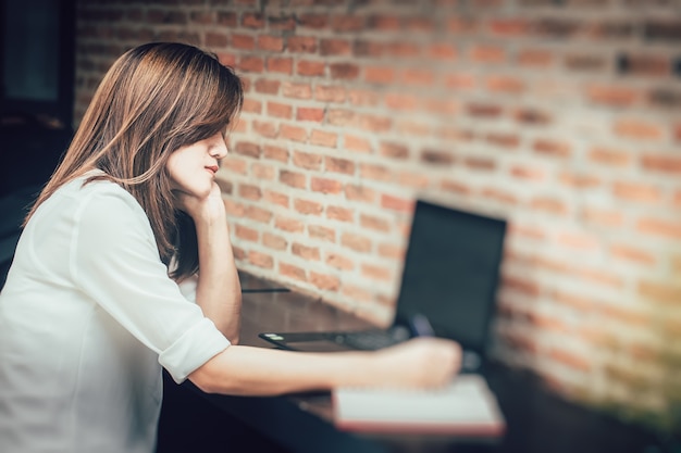 Ermüdungs-Frauen, die alleine beim Arbeiten denken und eine Anmerkung nehmen