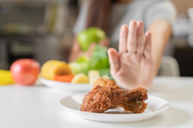 Ernährung Junge asiatische Frau oder Mädchen, die eine Diät machen, drängen Brathähnchen-Junk-Food ab und wählen grünen Apfel-Gemüse-Salat Essen für eine gute gesunde Gesundheit, wenn sie hungrig sind