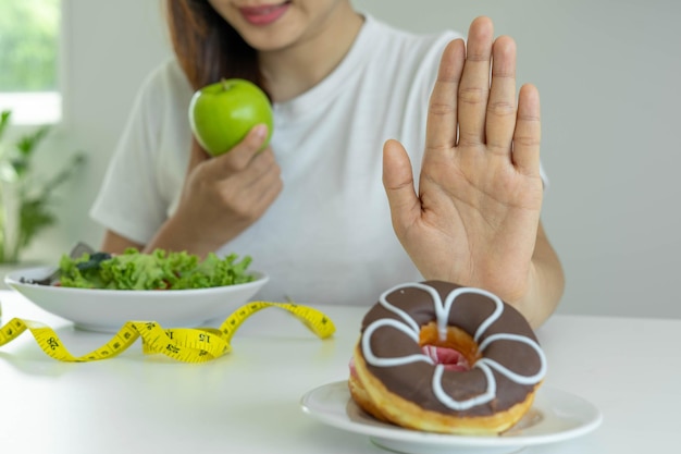 Ernährungskonzept Frauen weigern sich, Donuts zu essen und entscheiden sich für Apfel Gesunde Frauen und starke Körper