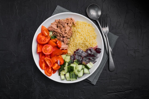 Ernährungskonzept Thunfischsalat Couscous-Salat mit konservierten Thunfisch-Tomaten-Gurken und violetten Zwiebeln auf dem Tisch Kopierbereich