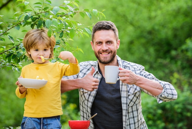 Ernährungswahl gesunde Ernährung und Diät Milchprodukte Morgenfrühstück Sohn und Vater essen glücklichen Vatertag Kleiner Junge mit Papa isst Müsli Familienbande Genießen Sie die Zeit zusammen