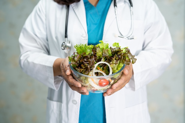 Ernährungswissenschaftler, der salatgemüselebensmittel in der glasschale hält.