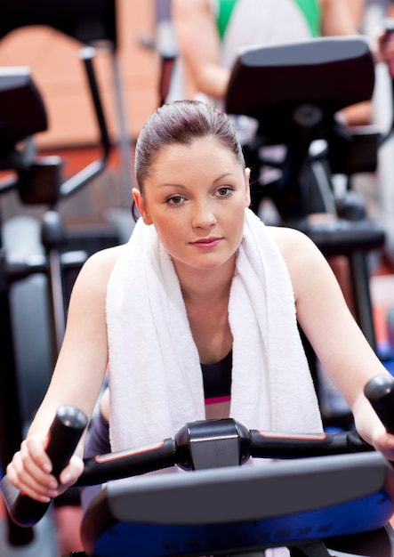 Ernste athletische Frau, die während eines Trainings in einer Sportzentrale radelt