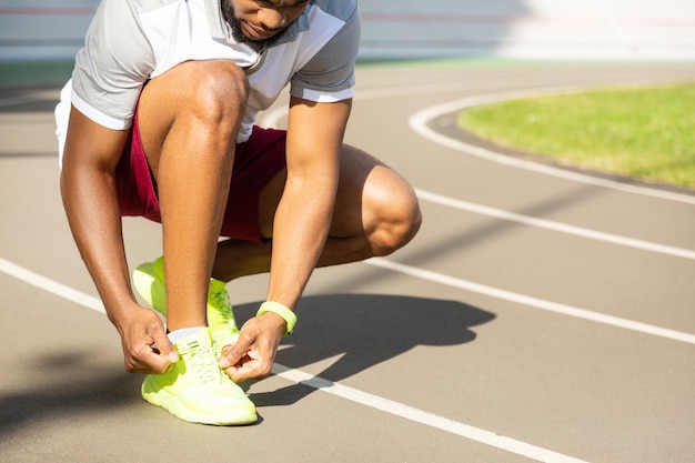 Ernster bärtiger afroamerikanischer athletischer Mann, der Schnürsenkel bindet