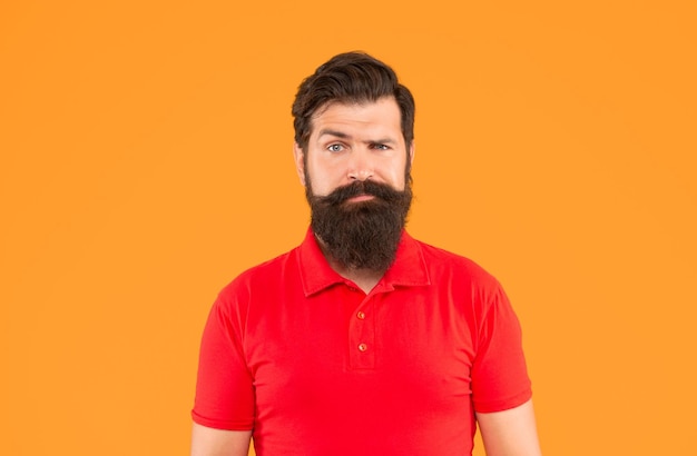 Ernster bärtiger Mann mit Schnurrbart im T-Shirt auf gelber Hintergrundhautpflege