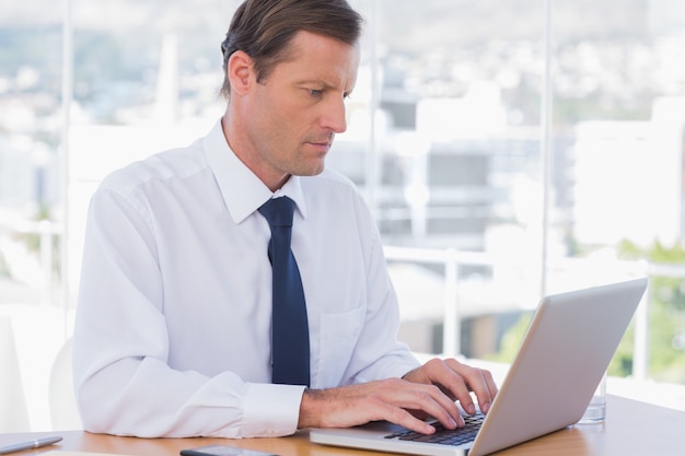 Ernster Geschäftsmann, der an einem Laptop arbeitet