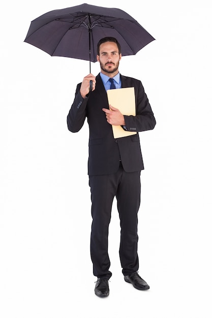 Ernster Geschäftsmann, der eine Datei unter Regenschirm hält