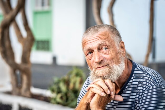 Ernster Gesichtsausdruck eines charmanten Mannes mit blauen Augen. 75-jähriger älterer Mann mit weißem Haar. Menschenkonzept