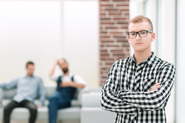 Ernster junger Mann, der in einem geräumigen Büro steht