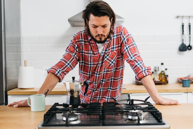 Foto ernster junger mann, der kaffee in der küche zubereitet