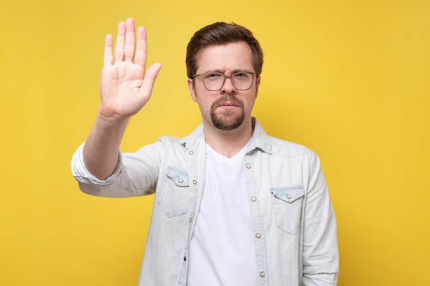 Ernster kaukasischer Mann, der die Hand hochhält Stop-Geste