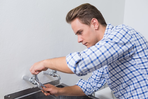 Ernster Klempner, der Wasserhahn mit Zangen repariert