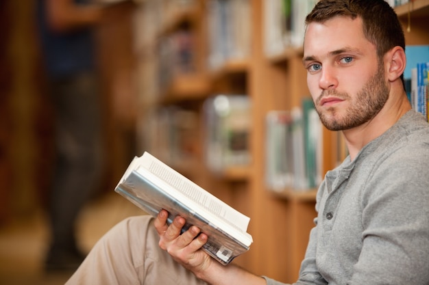 Ernster männlicher Student, der ein Buch hält