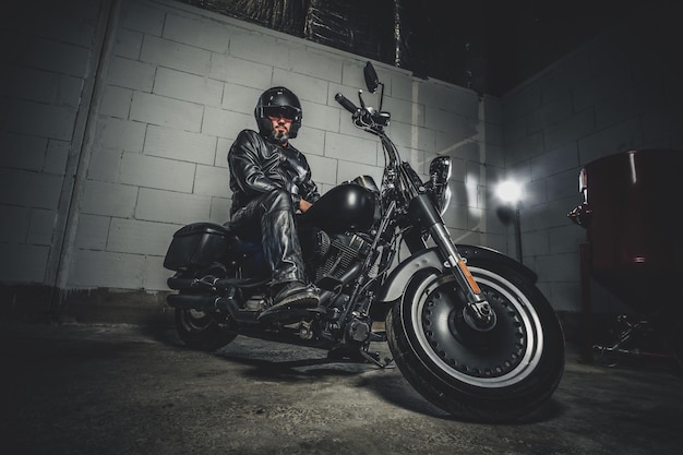Foto ernster mann in helm und schwarzem lederanzug sitzt auf seinem motorrad.