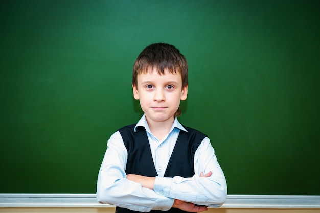 Ernster Schüler in der Nähe der grünen Schulbehörde im Klassenzimmer. Grundschulkind. Zurück zur Schule.