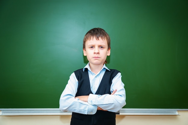 Ernster Schüler in der Nähe der grünen Schulbehörde im Klassenzimmer. Grundschulkind. Zurück zur Schule.