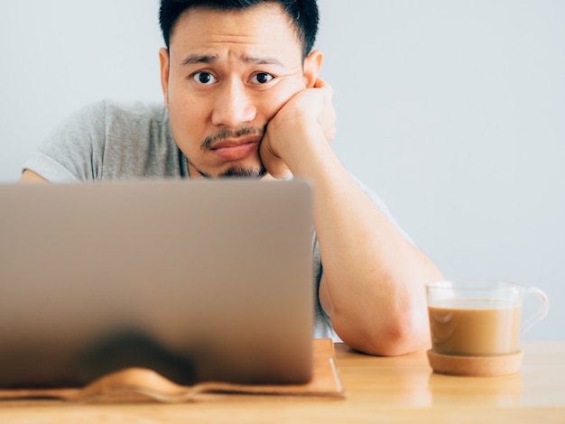 Ernstes und langweiliges Gesicht des Mannes arbeiten an Laptop.