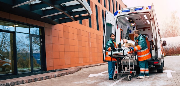 Ernstes und professionelles Team von Ärzten im Krankenwagen, die einen Patienten in einer Notsituation ins Krankenhaus bringen.