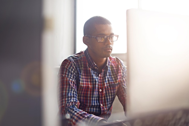 Ernsthaft denkender und kreativer Mann, der an seinem Computer arbeitet, während er über Innovationen recherchiert und liest