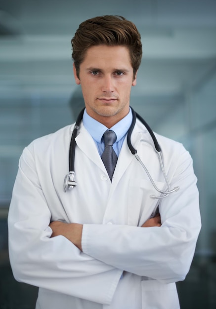 Ernsthaft gekreuzte Arme und Porträt eines männlichen Arztes mit Stethoskop für eine zuversichtliche Haltung Karriere Stolz und professioneller junger männlicher Gesundheitsarbeiter im medizinischen Büro eines Krankenhauses oder einer Klinik