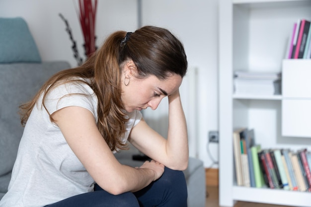 Ernsthafte depressive junge Frau, die auf der Couch sitzt Konzept der psychischen Gesundheit