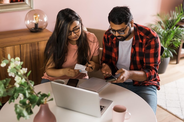 Ernsthafte Ehefrau und Ehemann, die Budgetprüfungsfinanzen planen, konzentrierten sich auf junge Frauen, die Online-Rechner verwendeten