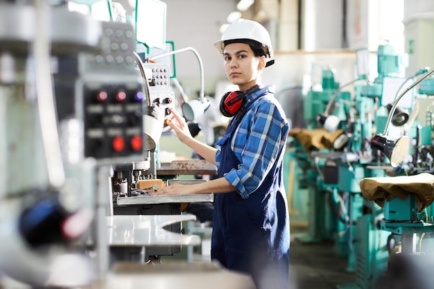 Ernsthafte Frau, die an der Produktionslinie arbeitet