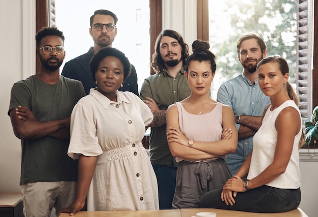 Ernsthafte Geschäftsleute, die mit verschränkten Armen stehen, selbstbewusst aussehen und Teamarbeit in einem Büro bei der Arbeit zeigen Porträt verschiedener kreativer Mitarbeiter, die Einheit und Erfolg zum Ausdruck bringen