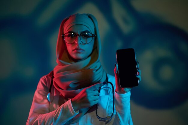 Foto ernsthafte junge ärztin im hijab mit einem telefon in der hand