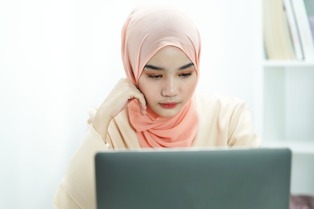 ernsthafte muslimische Studentin, die sich auf Prüfungstest oder Kursarbeit vorbereitet und Hausaufgabe macht.