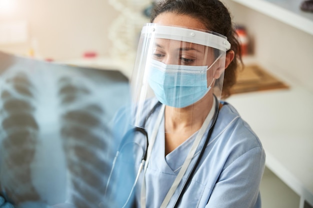 Ernsthafte Ärztin, die ein Röntgenbild der Brust untersucht