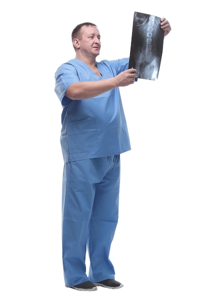 Ernsthafter Arzt, der ein Röntgenbild betrachtet, das auf einem weißen Hintergrund isoliert ist