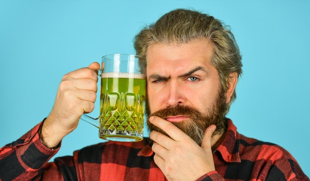 Ernsthafter homebrewer-erholung mann hält ein glas bier hipster an der theke und hat spaß beim fußballgucken brutaler bärtiger mann trinkt bier aus glas bierkneipe stilvoller barkeeper oder barmann in der bar 