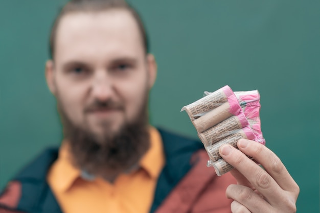 Ernsthafter junger Mann, der Kracher in seiner Hand hält.