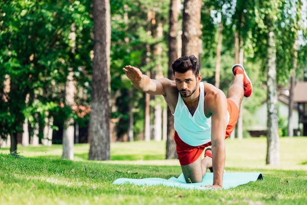 Ernsthafter Sportler trainiert auf Fitnessmatte im Park