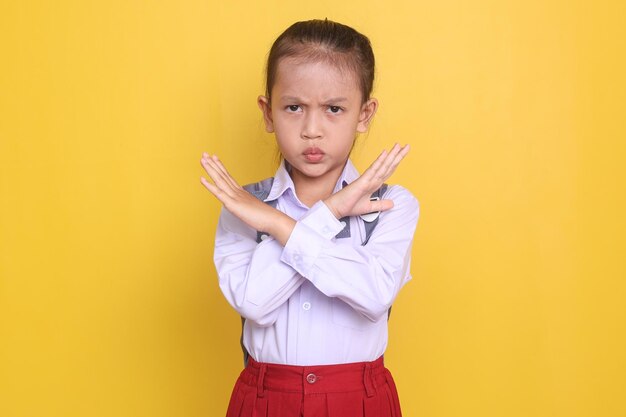 Foto ernsthaftes asiatisches kleines mädchen grundschüler kreuzt hände und schaut wütend in die kamera